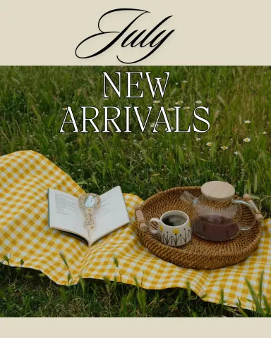 July New Arrivals. Photo of an open book and coffee on a yellow gingham picnic blanket outdoors.